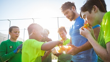 photo of children on a sports team eating snacks
