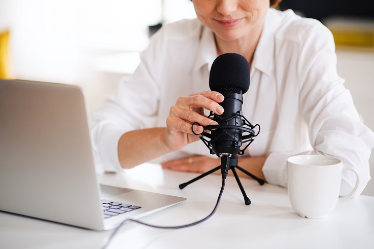 Photo of a person with a laptop speaking into a microphone.